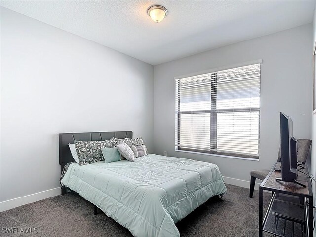 bedroom with dark carpet and a textured ceiling