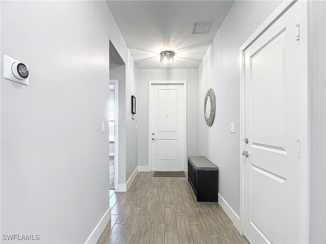 doorway with a textured ceiling and light hardwood / wood-style flooring