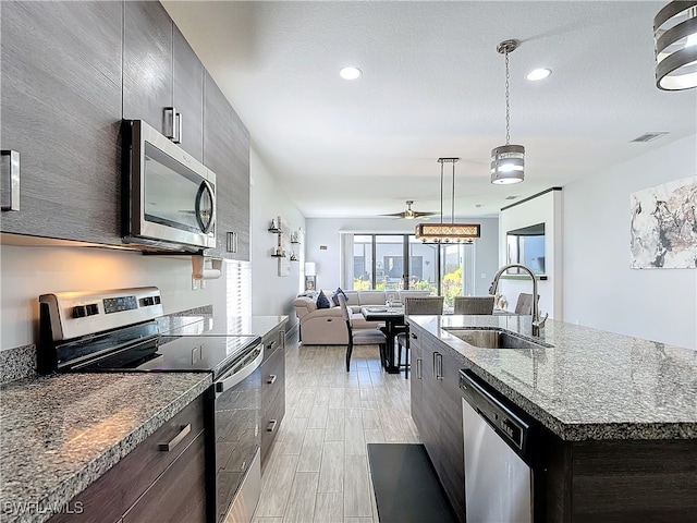 kitchen featuring pendant lighting, stainless steel appliances, sink, a center island with sink, and light hardwood / wood-style floors