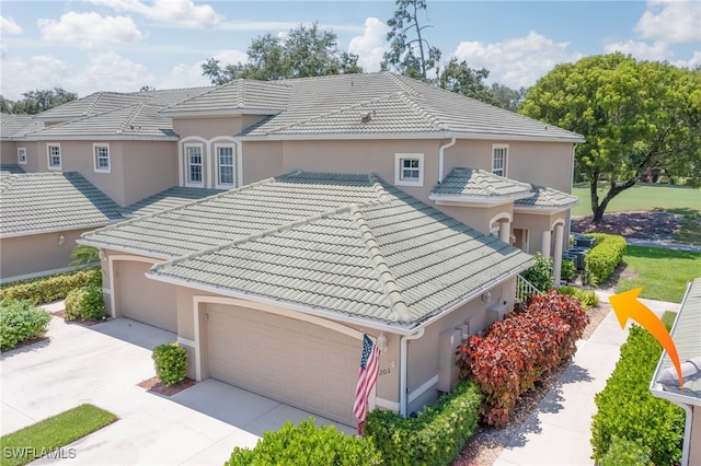 view of front of house featuring a tiled roof, stucco siding, driveway, and a garage