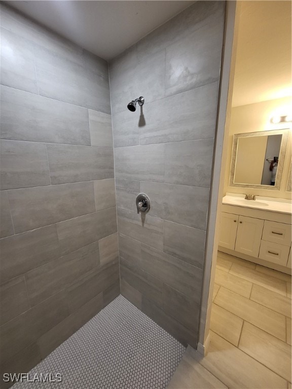 bathroom with a tile shower and vanity