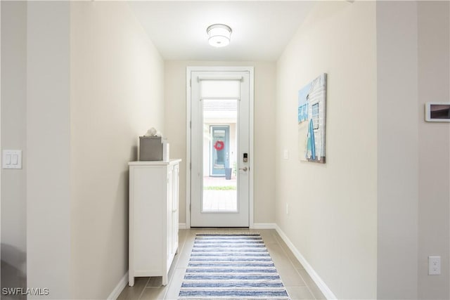 doorway with baseboards and light tile patterned floors