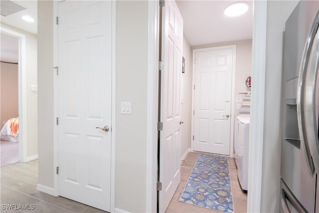 hallway featuring baseboards, visible vents, and wood finish floors