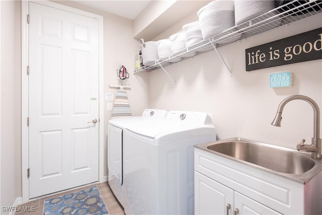 washroom featuring cabinet space, washing machine and dryer, and a sink