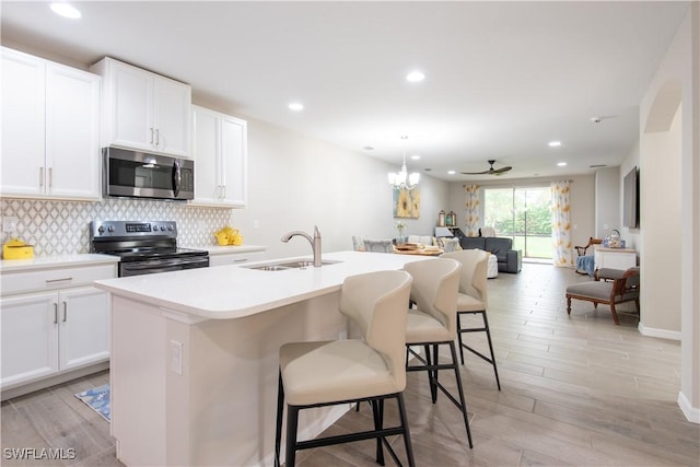 kitchen featuring tasteful backsplash, an island with sink, open floor plan, stainless steel appliances, and a sink