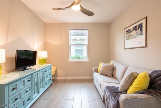 living room featuring light wood-style floors, ceiling fan, and baseboards