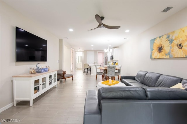 living room featuring recessed lighting, visible vents, baseboards, and ceiling fan with notable chandelier