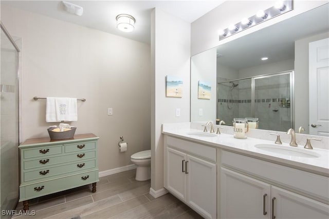 full bath featuring a sink, a shower stall, toilet, and double vanity