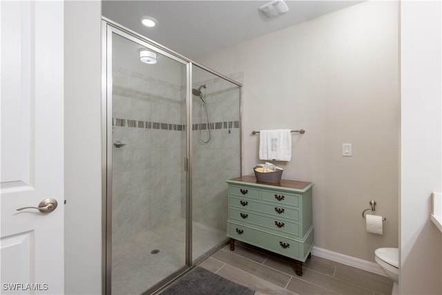 bathroom with a shower stall, toilet, and baseboards