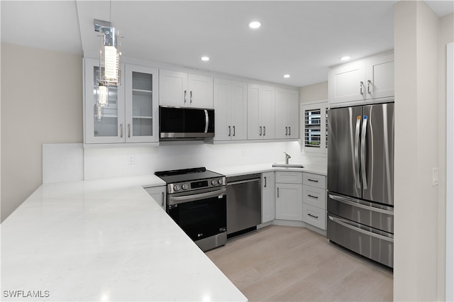 kitchen featuring a sink, glass insert cabinets, stainless steel appliances, and light countertops