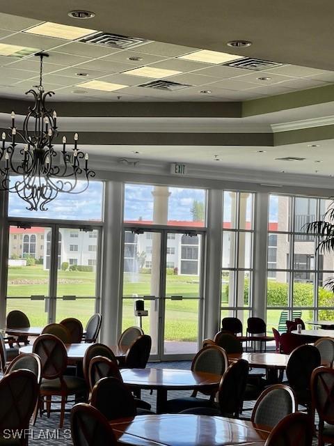 dining space featuring visible vents, a drop ceiling, and an inviting chandelier