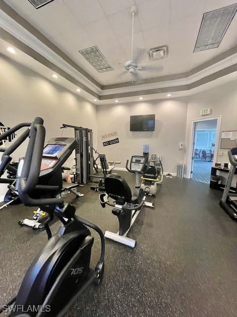 workout area featuring a tray ceiling, recessed lighting, a ceiling fan, and crown molding