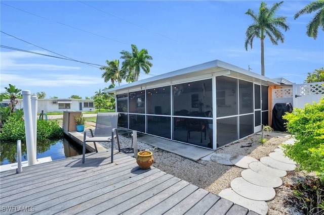 wooden terrace with a boat dock and a sunroom