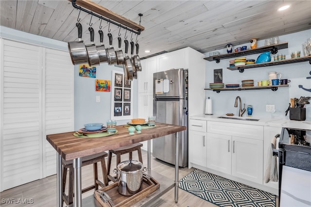 kitchen with appliances with stainless steel finishes, wood-type flooring, sink, and white cabinets