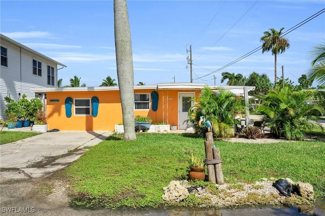 view of front facade featuring driveway, stucco siding, and a front yard