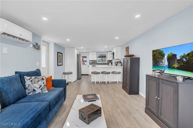 living room with a wall mounted air conditioner and light hardwood / wood-style flooring