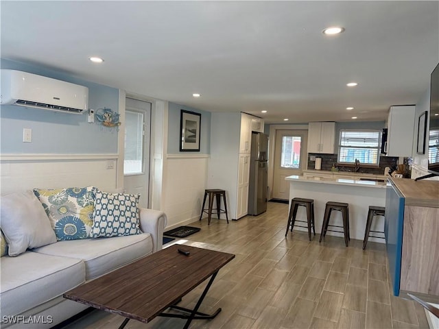 living room with recessed lighting, light wood-type flooring, and a wall mounted air conditioner