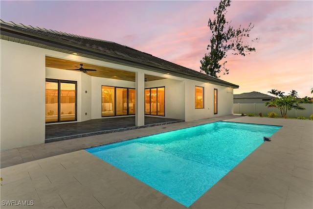 pool at dusk featuring a patio area and ceiling fan