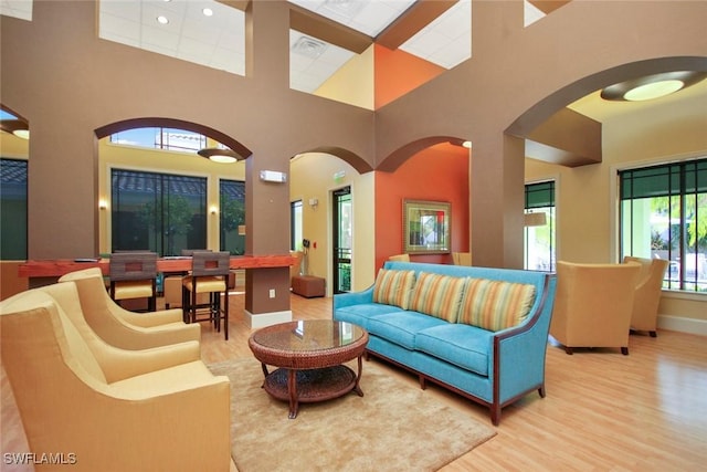 living area featuring visible vents, a high ceiling, light wood-style flooring, and baseboards