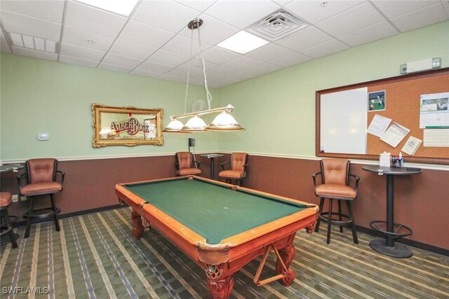 recreation room with a wainscoted wall, a drop ceiling, carpet flooring, and visible vents