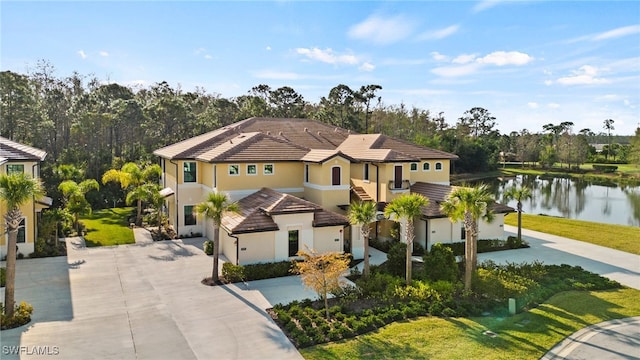 mediterranean / spanish-style home featuring concrete driveway, a tile roof, a water view, and stucco siding