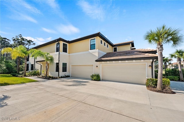 view of front facade featuring driveway, a tiled roof, and stucco siding