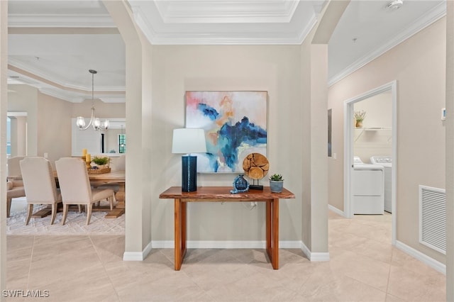 corridor featuring ornamental molding, light tile patterned floors, washer and dryer, and an inviting chandelier