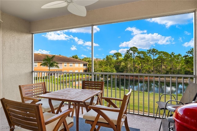 sunroom / solarium featuring a water view, a healthy amount of sunlight, and a ceiling fan