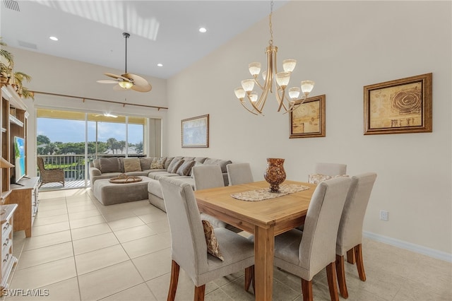 tiled dining area with ceiling fan with notable chandelier and a high ceiling