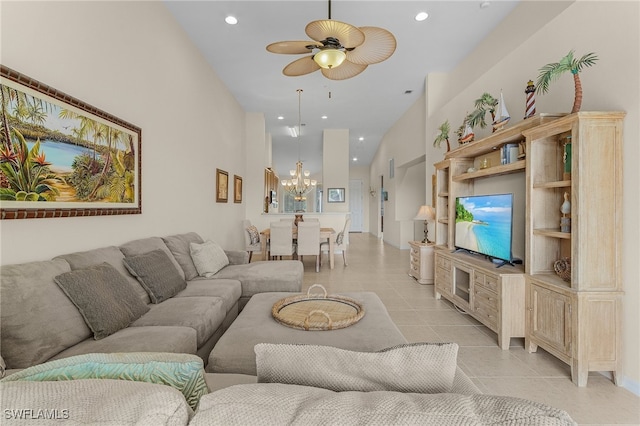 living room featuring ceiling fan with notable chandelier, a towering ceiling, built in shelves, and light tile patterned flooring