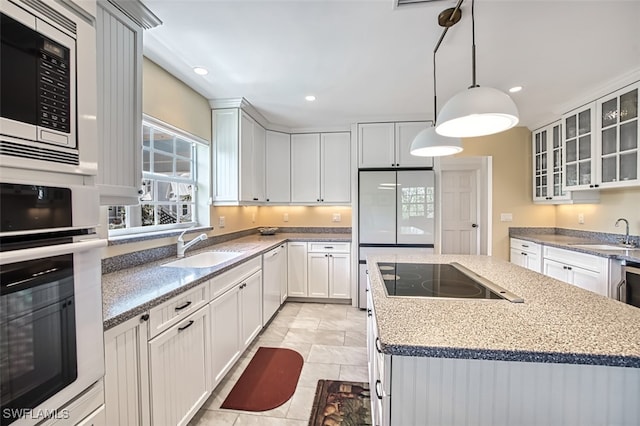 kitchen featuring white appliances, a kitchen island, glass insert cabinets, a sink, and recessed lighting