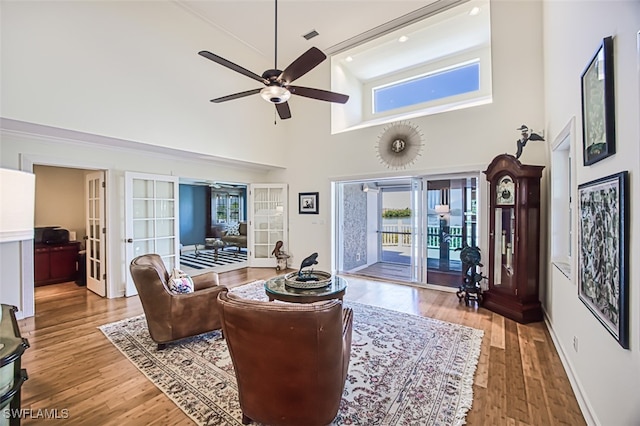 living area with ceiling fan, french doors, plenty of natural light, and wood finished floors