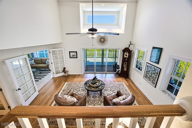 living room featuring french doors, wood finished floors, a towering ceiling, and a ceiling fan