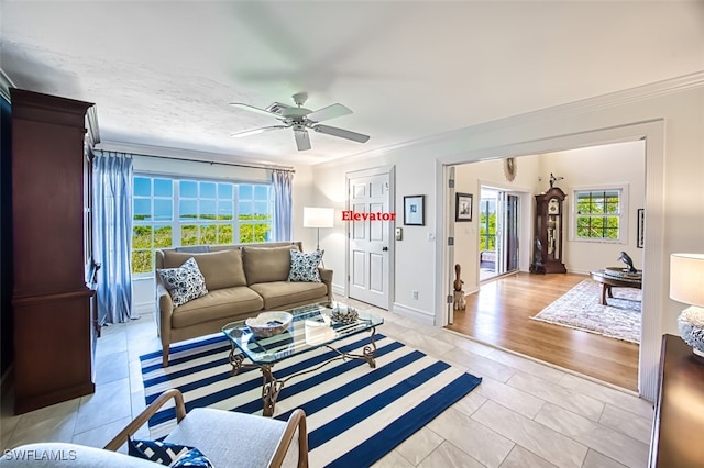 living area with a ceiling fan, light tile patterned flooring, crown molding, and baseboards