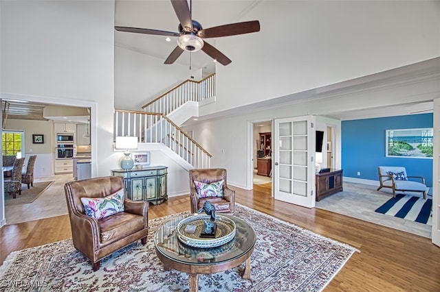 living area with stairs, a towering ceiling, wood finished floors, and a wealth of natural light