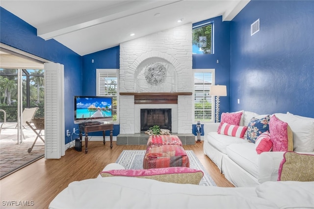 living room featuring vaulted ceiling with beams, hardwood / wood-style floors, and a fireplace