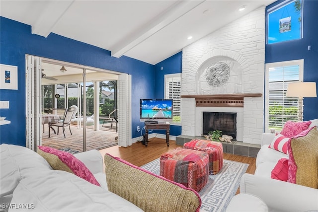 living room with hardwood / wood-style flooring, a stone fireplace, and vaulted ceiling with beams