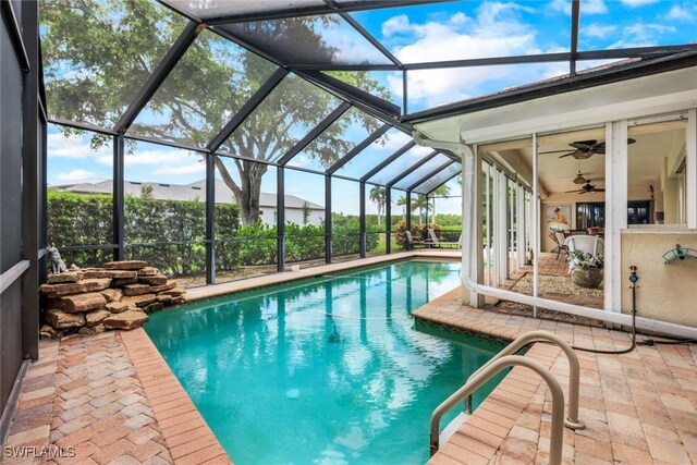 view of swimming pool featuring ceiling fan, a lanai, and a patio