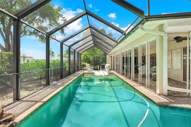 view of swimming pool featuring ceiling fan, a patio, and glass enclosure