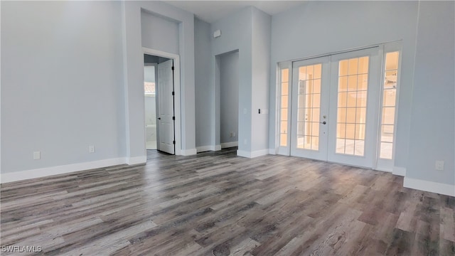 empty room with plenty of natural light, dark wood-type flooring, and french doors