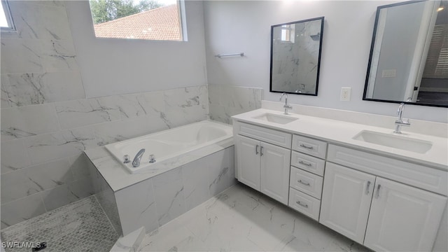 bathroom featuring a wealth of natural light, tiled tub, and vanity