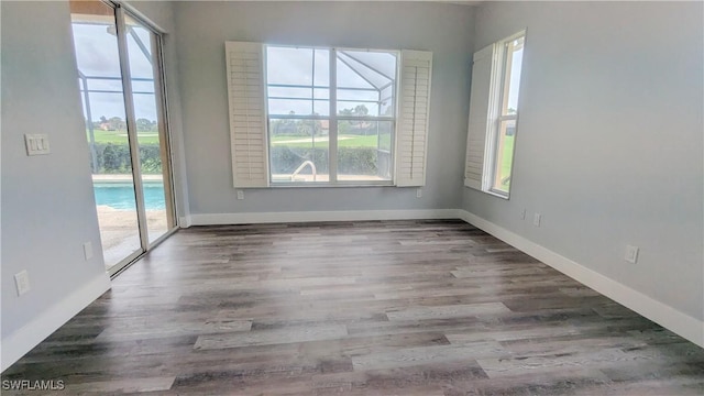 6733 Bent Grass Dr, Naples, FL 34113 - empty room featuring baseboards, wood finished floors, and a healthy amount of sunlight