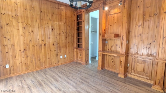 unfurnished room featuring light wood-type flooring and wood walls