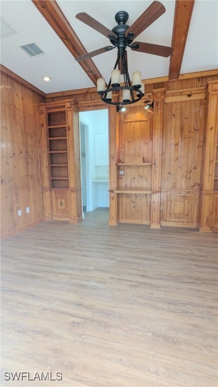 unfurnished living room featuring ceiling fan, wood walls, and light wood-type flooring