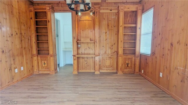 6733 Bent Grass Dr, Naples, FL 34113 - spare room with a notable chandelier, wood walls, and wood finished floors