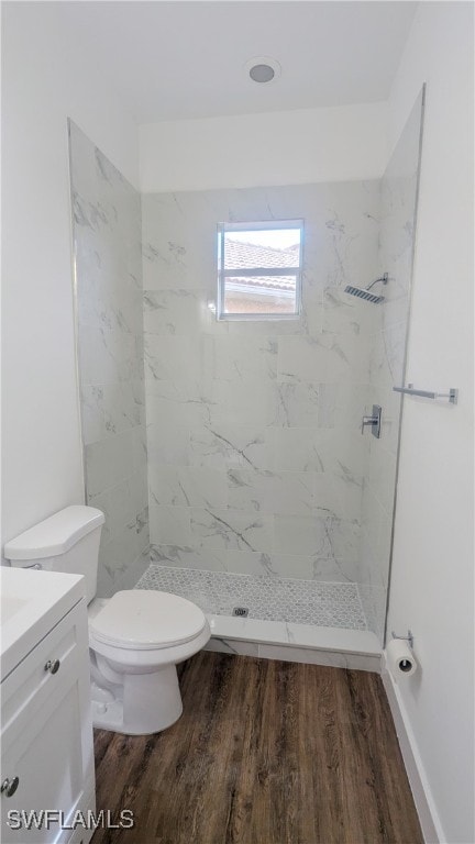 bathroom featuring vanity, toilet, hardwood / wood-style floors, and tiled shower