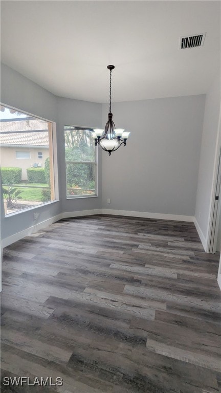 unfurnished dining area featuring a chandelier and dark hardwood / wood-style floors