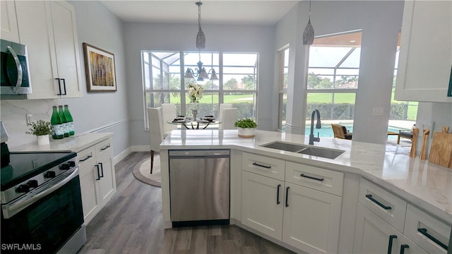 kitchen with a wealth of natural light, appliances with stainless steel finishes, and white cabinetry