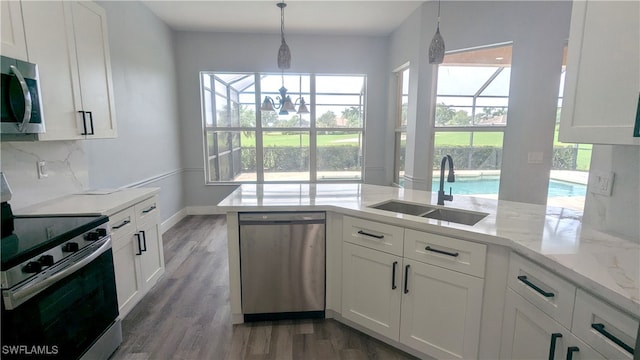 kitchen with a wealth of natural light, appliances with stainless steel finishes, and white cabinetry