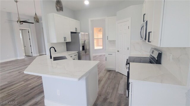6733 Bent Grass Dr, Naples, FL 34113 - kitchen with a peninsula, appliances with stainless steel finishes, a sink, light wood-type flooring, and light stone counters